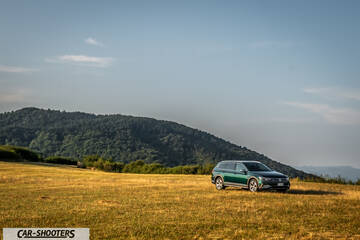 Volkswagen Passat Alltrack – front three-quarter, dark green against a mountain backdrop