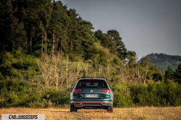 Volkswagen Passat Alltrack – rear view, green metallic against a wooded hillside