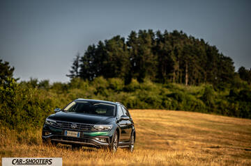 Volkswagen Passat Alltrack – front three-quarter, dark green metallic in a grassy field