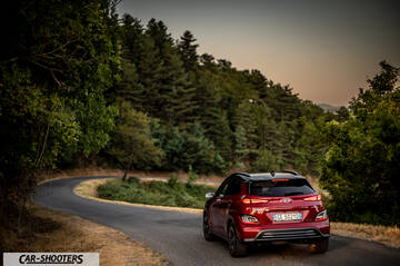 Hyundai Kona Electric 2021 &ndash; rear three-quarter, red on a winding country road