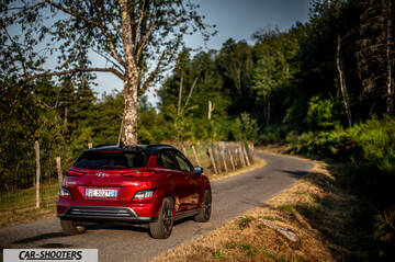 Hyundai Kona Electric 2021 – rear three-quarter, red metallic on a country road