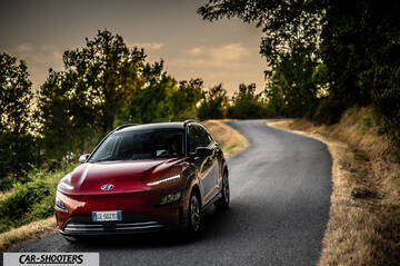 Hyundai Kona Electric 2021 – front three-quarter, dark red on a country road