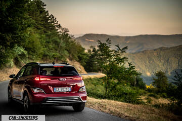 Hyundai Kona Electric 2021 – rear three-quarter, dark red on a winding mountain road