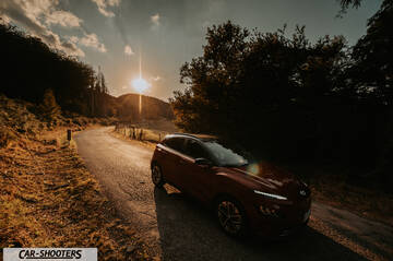 Hyundai Kona Electric 2021 – front three-quarter, dark red on a country road