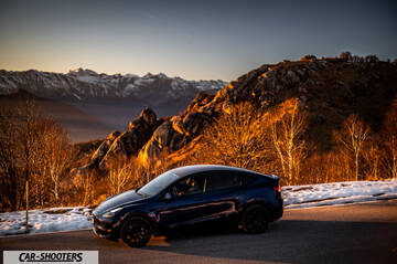 Tesla Model Y – side profile, dark blue against a mountain backdrop