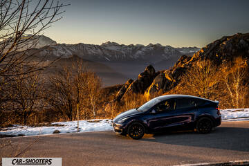 Tesla Model Y – side profile, dark blue against a mountain backdrop