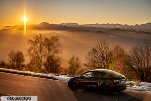 Tesla Model Y – rear three-quarter, black against a mountain backdrop at sunset