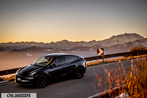 Tesla Model Y – front three-quarter, dark blue against a mountain backdrop