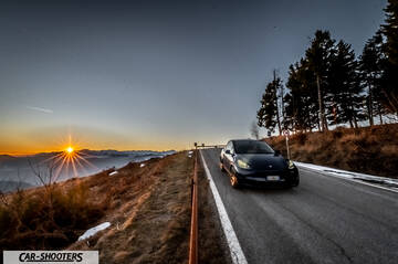 Tesla Model Y – front three-quarter, dark blue on a mountain road at sunset