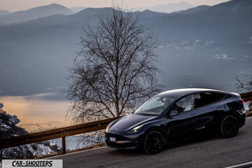 Tesla Model Y – front three-quarter, dark blue against a mountain backdrop