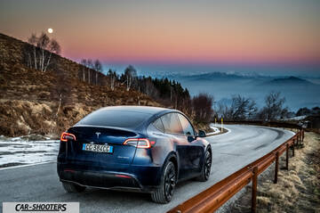 Tesla Model Y – rear three-quarter, dark blue on a winding mountain road