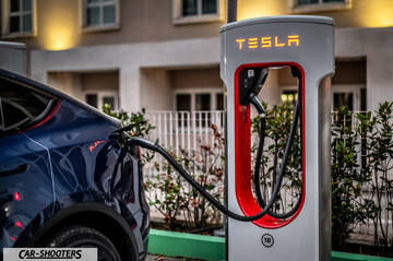 Tesla Model Y – rear three-quarter, dark blue at a tesla supercharger