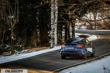 Tesla Model Y – rear view, dark blue on a winding snowy road