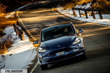 Tesla Model Y – front three-quarter, dark blue on a winding road