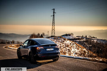 Tesla Model Y – rear three-quarter, dark blue on a winding mountain road