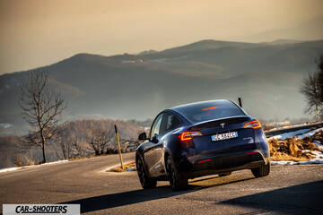 Tesla Model Y – rear three-quarter, dark blue against a mountain backdrop