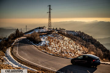 Tesla Model Y – rear three-quarter, black on a winding mountain road