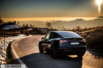 Tesla Model Y – rear three-quarter, dark blue on a winding mountain road