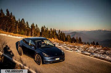 Tesla Model Y – front three-quarter, dark blue on a mountain road