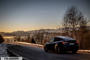 Tesla Model Y – rear three-quarter, dark blue on a winding mountain road