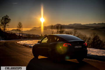 Tesla Model Y – rear three-quarter, black against a mountain backdrop