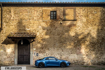 Alpine A110 – side profile, blue against an old stone wall