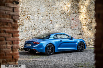Alpine A110 – rear three-quarter, blue metallic against a stone wall