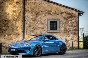Alpine A110 – front three-quarter, blue metallic parked against a stone wall