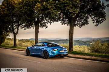 Alpine A110 – rear three-quarter, blue metallic on a country road