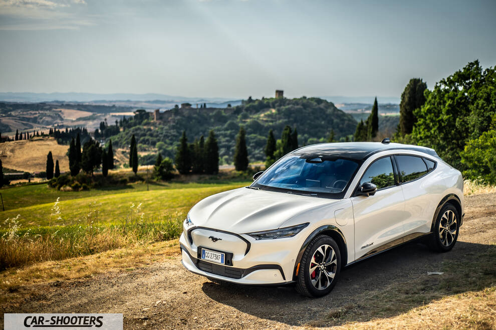 Ford Mustang Mach E – front three-quarter, white against a mountainous countryside backdrop