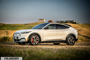 Ford Mustang Mach E – side profile, white on a rural dirt field