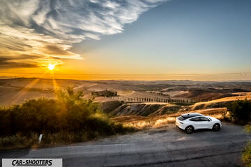 Ford Mustang Mach E – rear three-quarter, white against a sunset landscape backdrop