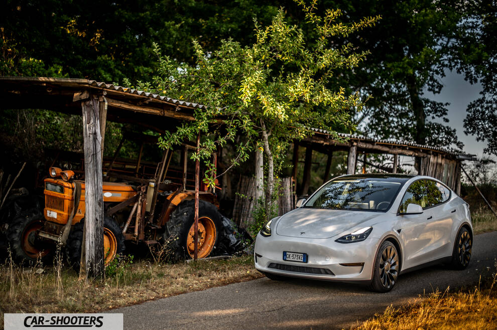 Tesla Model Y Performance – front three-quarter, white on a rural road next to an old tractor
