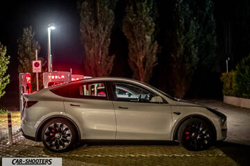 Tesla Model Y Performance – side profile, white at night near charging stations