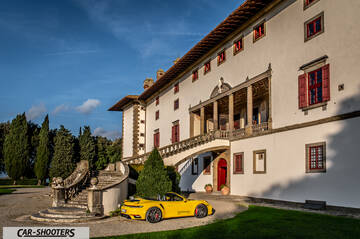 Porsche 911 Turbo Cabrio – rear three-quarter, yellow against a historic villa backdrop