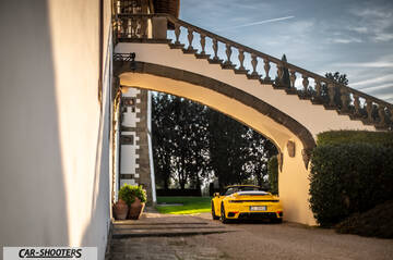 Porsche 911 Turbo Cabrio – rear three-quarter, yellow under an arched stone bridge