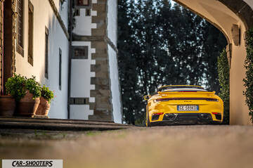 Porsche 911 Turbo Cabrio – rear view, yellow framed by an old stone archway