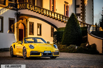 Porsche 911 Turbo Cabrio – front three-quarter, yellow in front of a historic building
