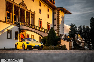 Porsche 911 Turbo Cabrio – front three-quarter, yellow against a historic building backdrop