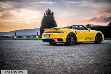 Porsche 911 Turbo Cabrio – rear three-quarter, yellow on a gravel courtyard