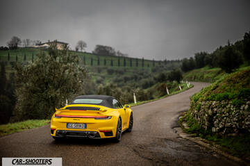 Porsche 911 Turbo Cabrio – rear three-quarter, yellow on a winding country road