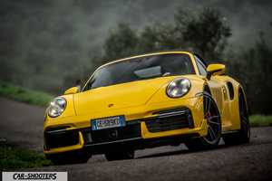 Porsche 911 Turbo Cabrio – front three-quarter, yellow on a winding country road