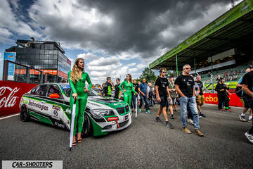 front three-quarter, white with green livery at a racetrack paddock