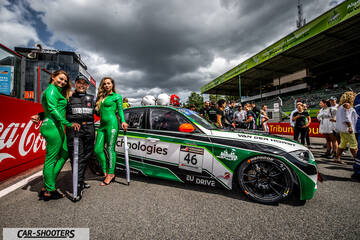 front three-quarter, white with green and black at a racetrack with people