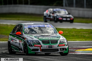 front three-quarter, white with green and black graphics on a racing track