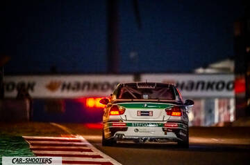 rear view, white with green and black accents on a race track at night