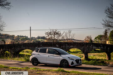 Hyundai i2N – front three-quarter, white on a country road with a stone bridge