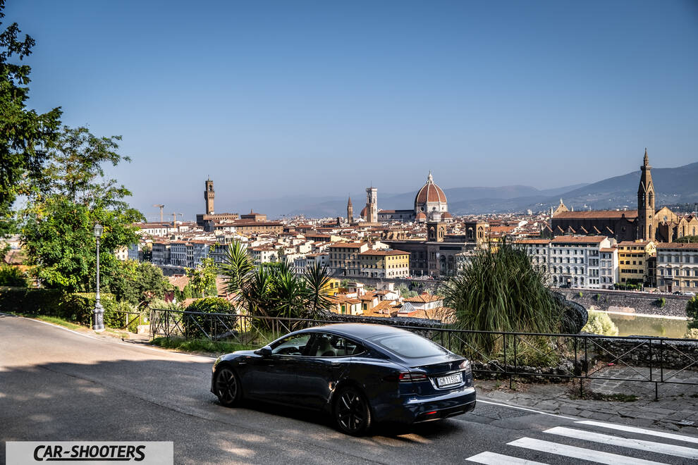 Tesla Model S Plaid – rear three-quarter, dark blue against a city skyline backdrop
