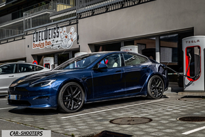 Tesla Model S Plaid – side profile, dark blue metallic at a supercharger station
