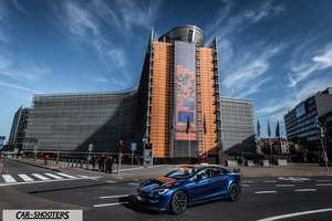 Tesla Model S Plaid – front three-quarter, blue in front of a large modern building